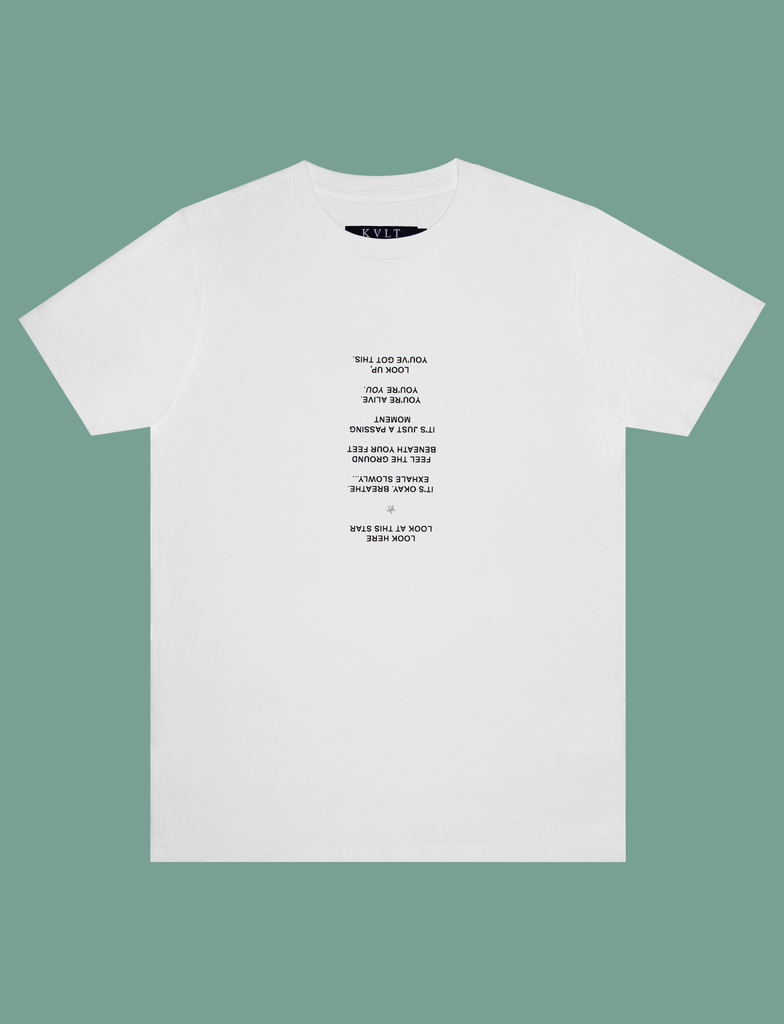 Front view of the PAUSE Tee in White by KULT Clothing | It reads "Look here. Look at this star. It's okay. Breathe. Exhale slowly... Feel the ground beneath your feet. It's just a passing moment. You're alive. You're YOU. Look up, you've got this." printed using our matte black and silver glitter Barely There™ vinyl | eco-friendly, climate neutral t-shirt