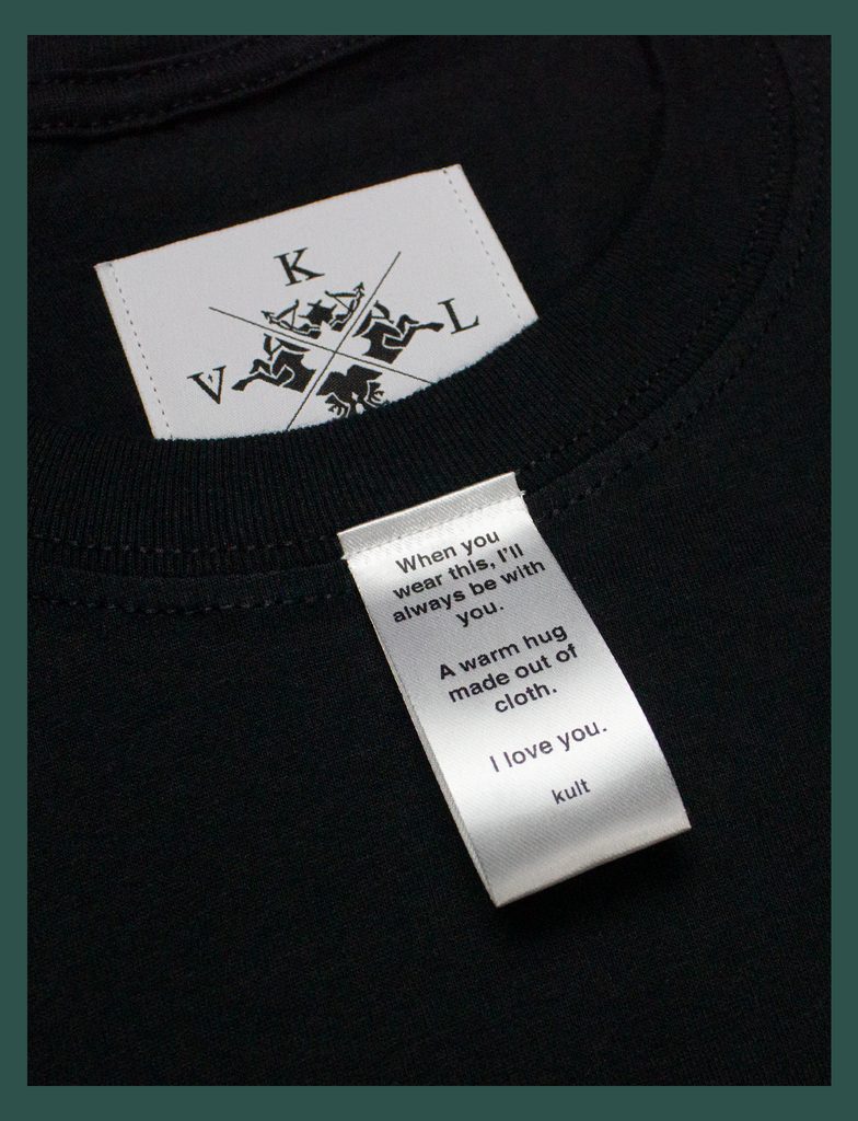 Close-up on the label of A WARM HUG Tee in Black by KULT Clothing | When you wear this, I'll always be with you. A warm hug made out of cloth. I love you. KULT