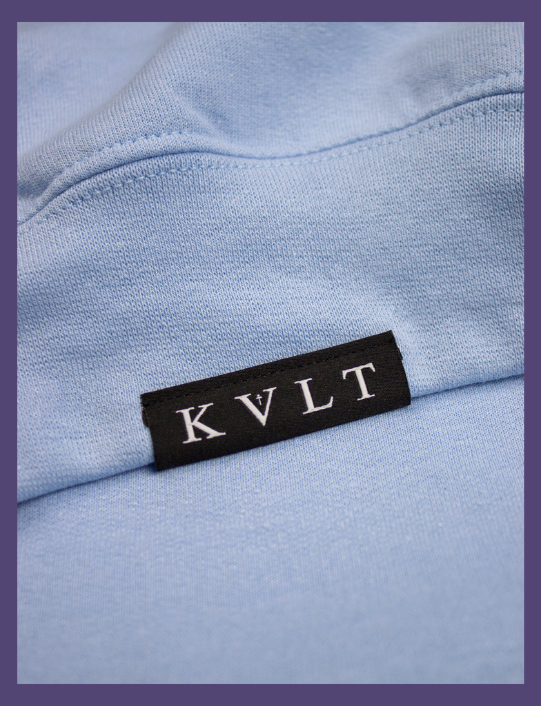 Close-up shot of the topside hem tag on the A WARM HUG Sweater in Light Blue by KULT Clothing | When you wear this, I'll always be with you. A warm hug made out of cloth. I love you. KULT | KVLT