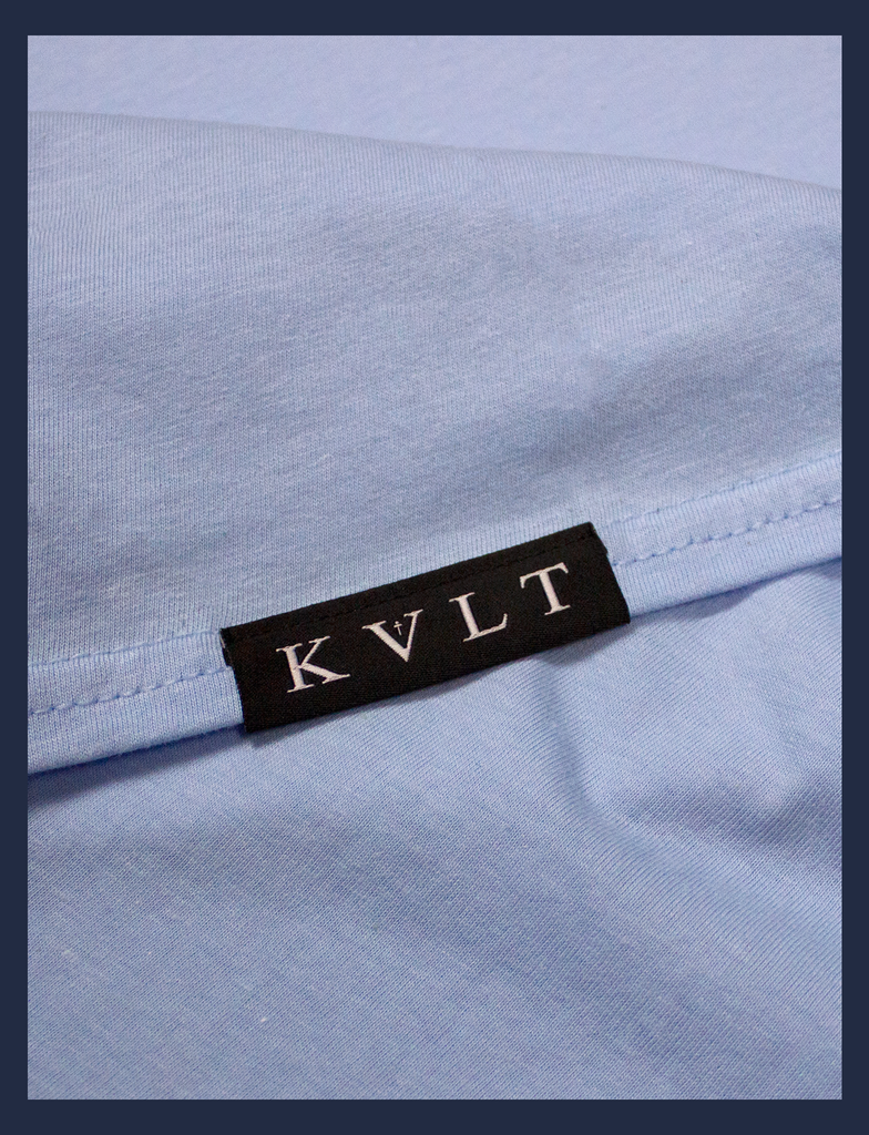 Close-up on the bottom seam label of A WARM HUG Tee in Light Blue by KULT Clothing | When you wear this, I'll always be with you. A warm hug made out of cloth. I love you. KULT