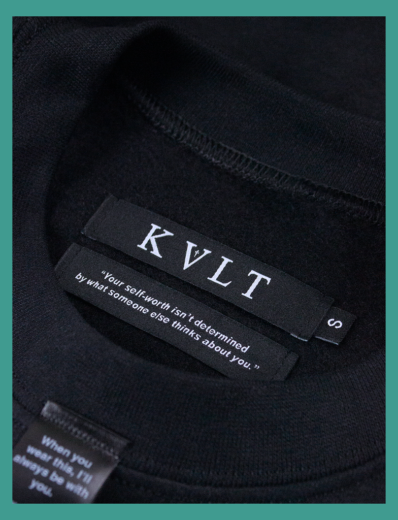 Close-up shot of the self-worth twin labels on the A WARM HUG Sweater in Black by KULT Clothing | "Your self-worth isn't determined by what someone else thinks about you."