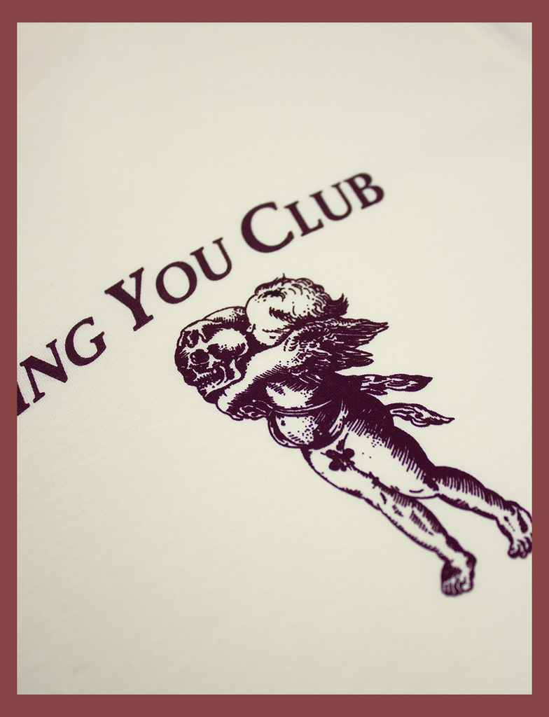 Close-up view of the hand-printed design on the CAN'T STOP LOVING YOU CLUB Tee by KULT Clothing | It reads "Can't Stop Loving You Club" next to an illustration of a cherub holding a skull | Hand-printed using eco friendly inks