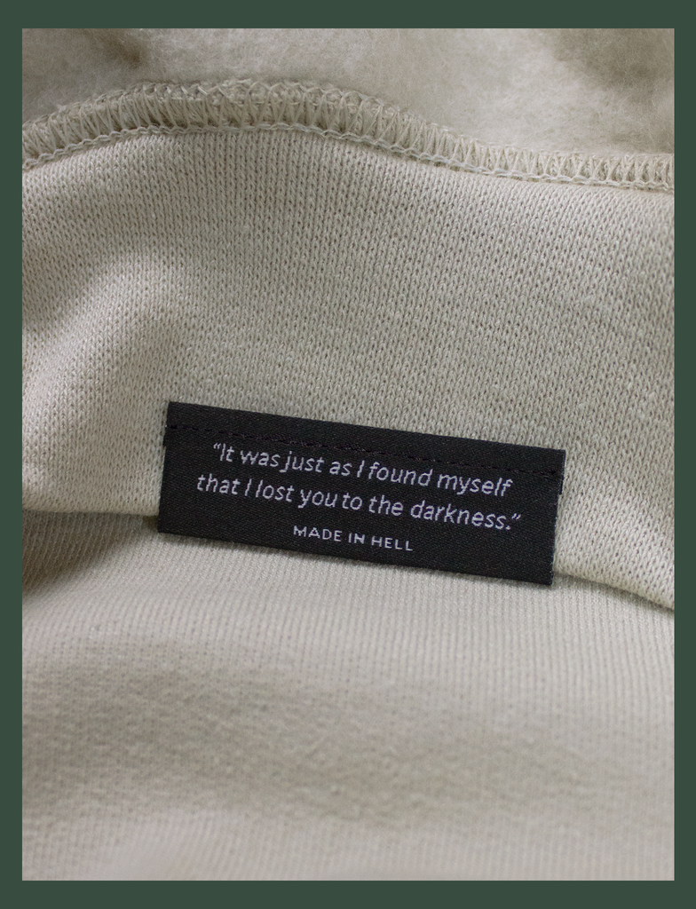 Close-up shot of the underside hem tag on the DISTANT LOVE Sweater in Sandstone by KULT Clothing | "It was just as I found myself that I lost you to the darkness." MADE IN HELL | KVLT