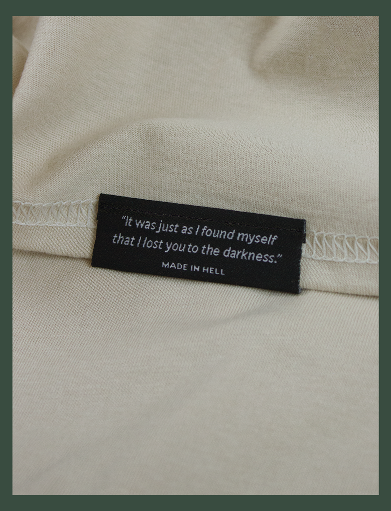 Close-up shot of the underside hem tag on the DISTANT LOVE Tee in Sandstone by KULT Clothing | "It was just as I found myself that I lost you to the darkness." MADE IN HELL | KVLT