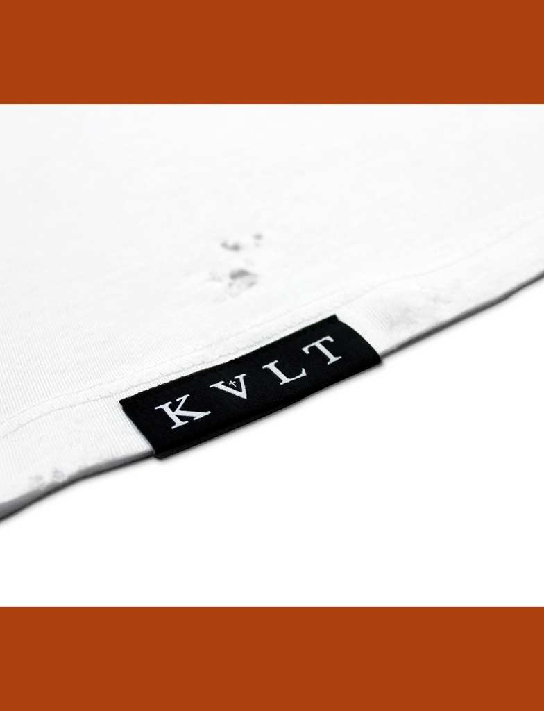 Close-up of the hem branding on the DISTRESSED BASIK Tee in White