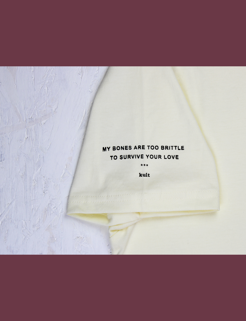 Close-up of the sleeve on the GARDEN OF DEATH Tee in Primrose by KULT Clothing | eco-friendly, climate neutral t-shirt, "MY BONES ARE TOO BRITTLE FOR YOU LOVE"