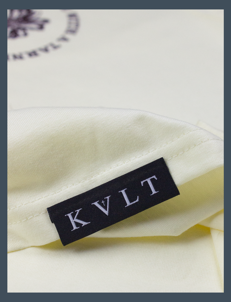 Close-up view of the topside hem tag detailing on the SADIFORNIA Tee in Primrose by KULT Clothing | eco-friendly, climate neutral t-shirt | KVLT
