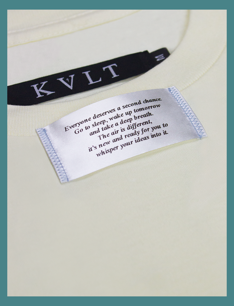 Close-up view of the appliqué label attached at the neckline on the SECOND CHANCE Tee by KULT Clothing | It reads "Everyone deserves a second chance. Go to sleep, wake up tomorrow and take a deep breath. The air is different, it's new and ready for you to whisper your ideas into it" | HD printed premium heavyweight satin label, featuring blue accent stitching.