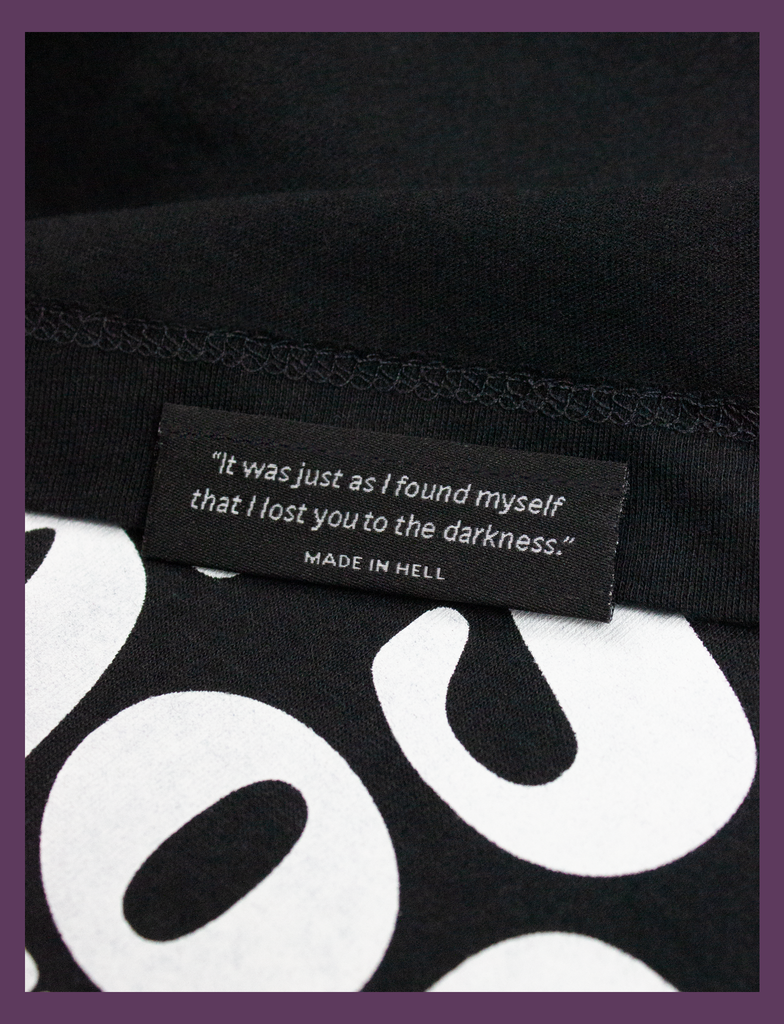 Close-up detailing of the underside hem label on THE JOY OF SATAN Tee in Black by KULT Clothing | The Joy of Satan | A Gourmet Guide to Sinning | KVLT