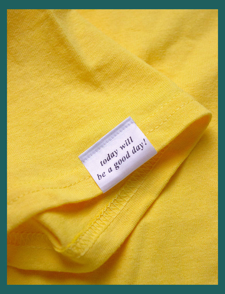 View of the topside of the appliqué label attached at the right cuff on the GOOD DAY Tee by KULT Clothing | It reads "today will be a good day!" in an italicised font | HD printed premium heavyweight satin label