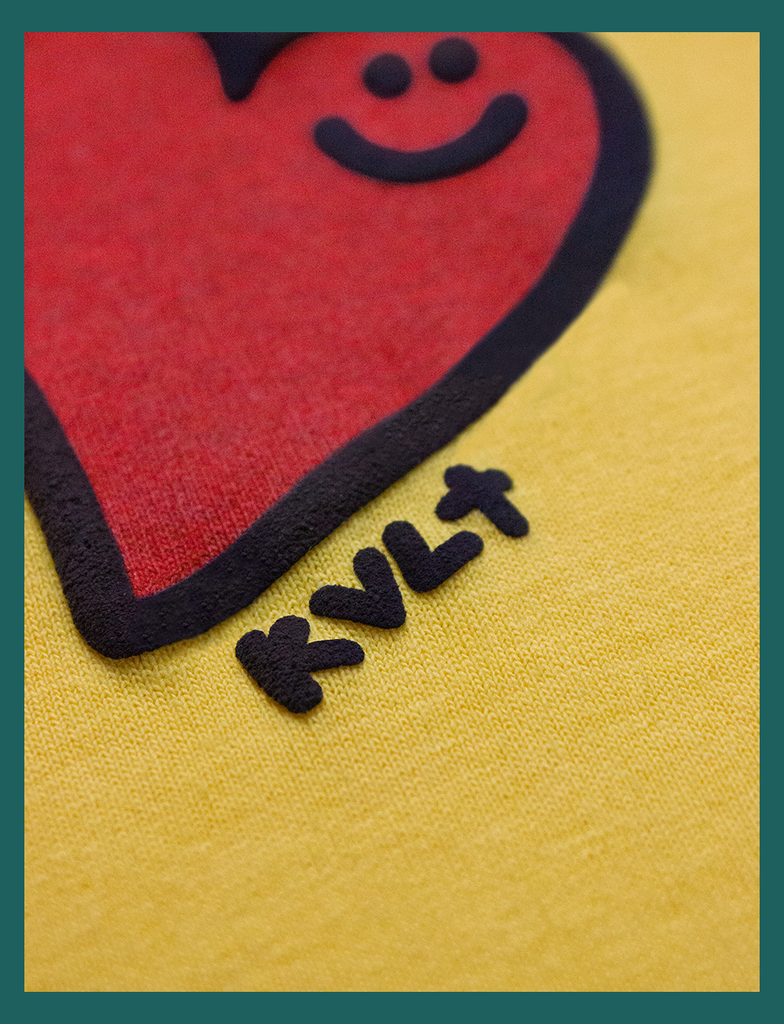 Super close-up view of the detail on the hand-printed design in the centre of the chest on the GOOD DAY Tee by KULT Clothing | The design features a smiling heart with a puff effect finished with "KVLT" at the edge | Hand-printed using eco friendly inks