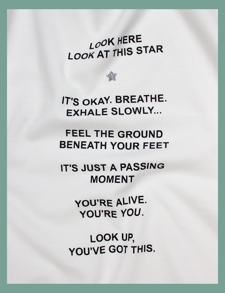 A full close-up view of the  design on the PAUSE Tee in White by KULT Clothing | It reads "Look here. Look at this star. It's okay. Breathe. Exhale slowly... Feel the ground beneath your feet. It's just a passing moment. You're alive. You're YOU. Look up, you've got this." | Printed using our matte black and silver glitter Barely There™ vinyl