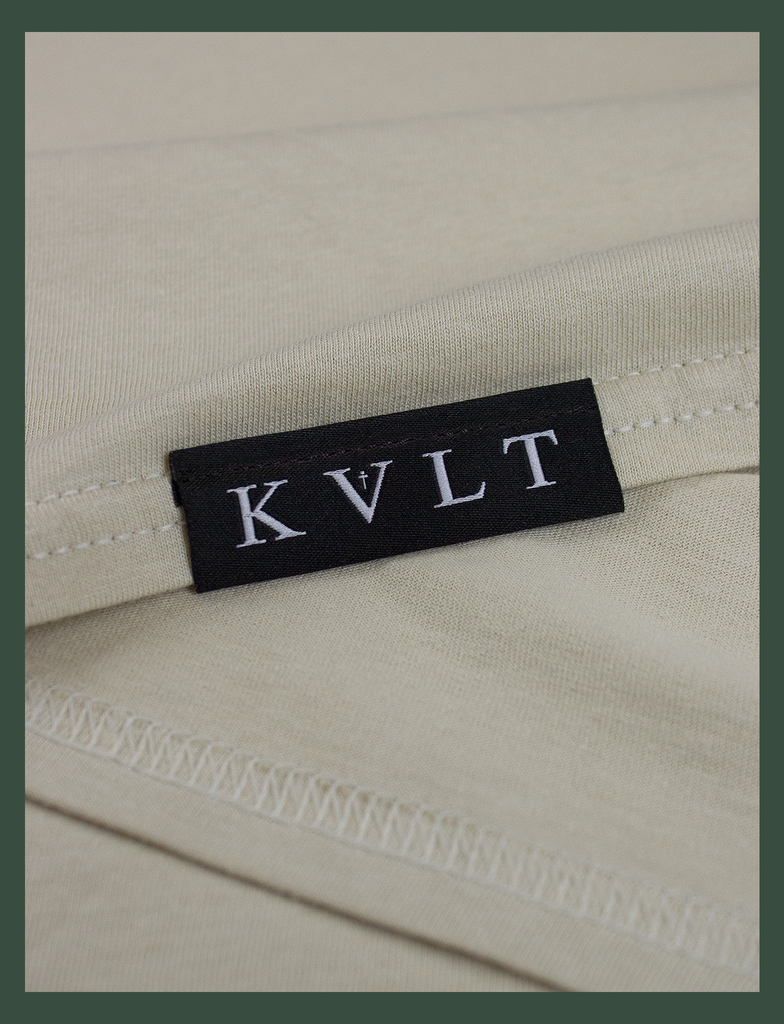 Close-up shot of the topside hem tag on the DISTANT LOVE Tee in Sandstone by KULT Clothing | I love it when you miss me. I love when I can feel you hugging me when you aren’t even nearby. You’re like a clothing label brushing against the back of my neck, reminding me I’m loved. KULT | KVLT