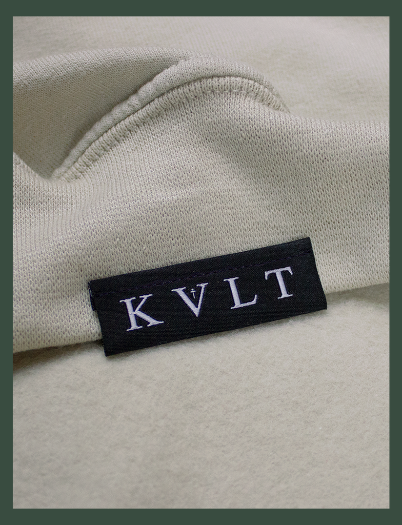 Close-up shot of the topside hem tag on the DISTANT LOVE Sweater in Sandstone by KULT Clothing | I love it when you miss me.  I love when I can feel you hugging me when you aren’t even nearby.  You’re like a clothing label brushing against the back of my neck, reminding me I’m loved. KULT | KVLT