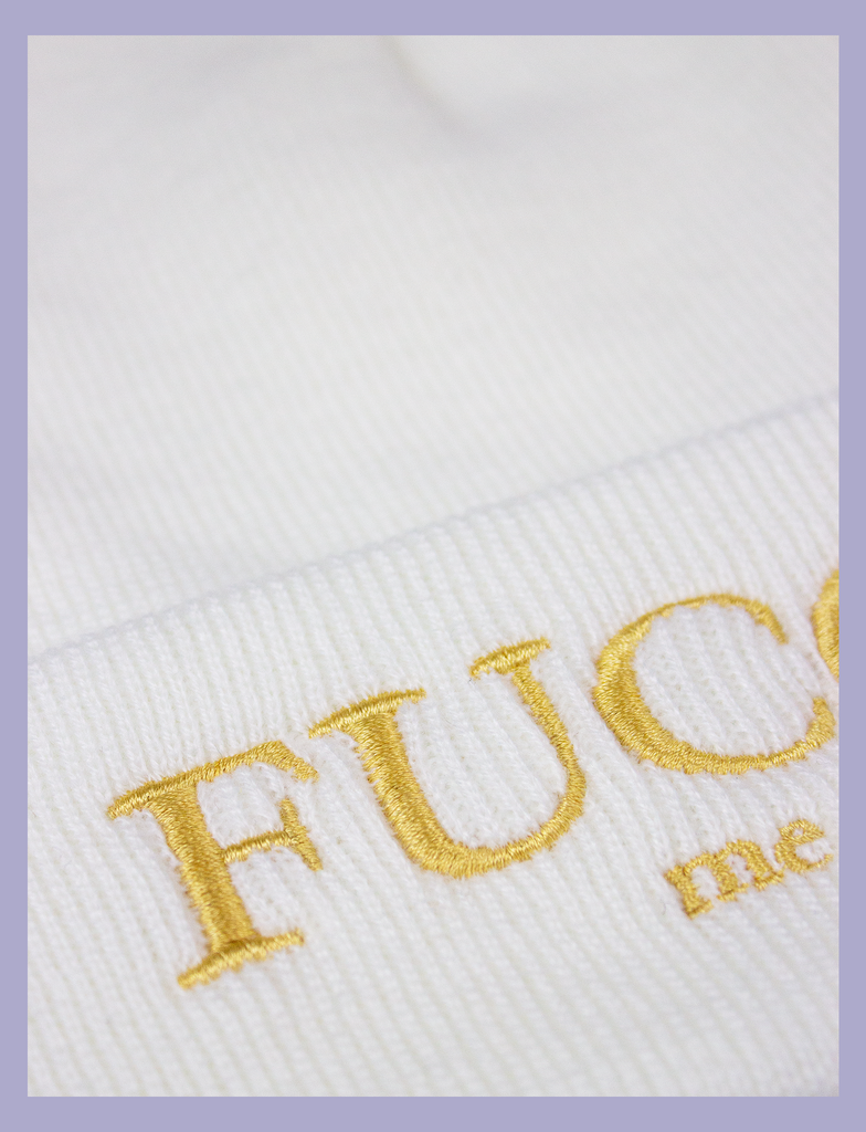 Close-up of the design on the FUCCI ME Beanie by KULT Clothing | "Fucci Me" embroidered design in gold thread on a white acrylic beanie hat