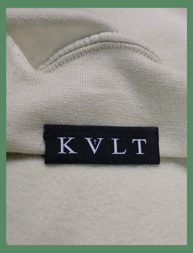 Close-up shot of the topside hem tag on the GROWTH Sweater in Sandstone by KULT Clothing | Super HD Woven Hem Label | KULT
