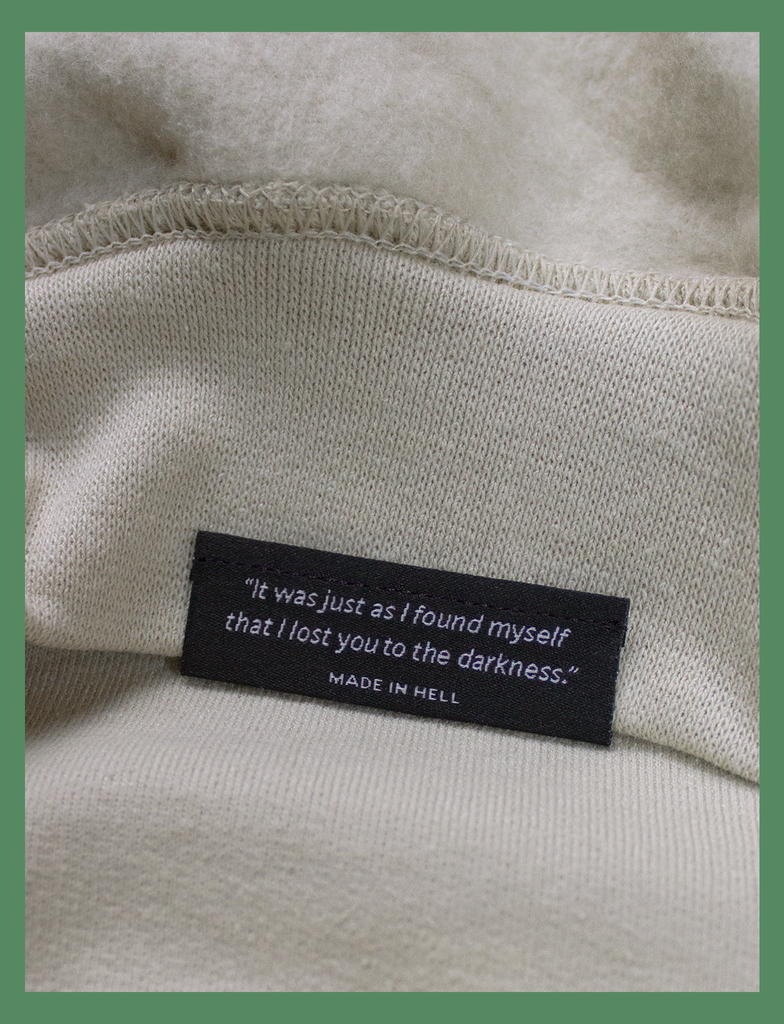 Close-up shot of the underside hem tag on the GROWTH Sweater in Sandstone by KULT Clothing | "It was just as I found myself that I lost you to the darkness." MADE IN HELL | KULT