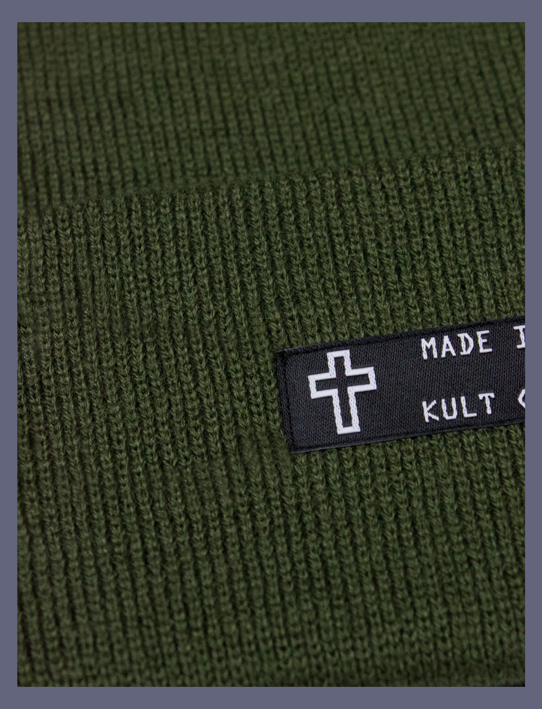Close-up detail on the MADE IN HELL Beanie in Forest Green by KULT Clothing | Black appliqué label on the front of a forest green, 100% acrylic knit beanie hat