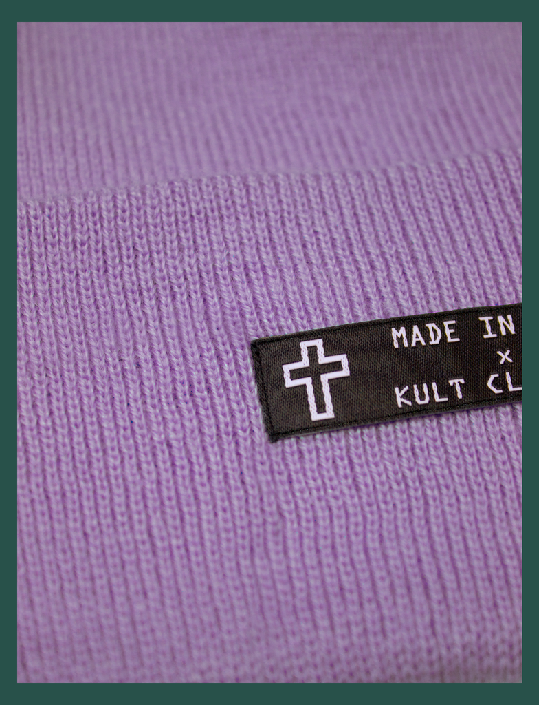 Close-up detail on the MADE IN HELL Beanie in Lavender by KULT Clothing | Black appliqué label on the front of a lavender-coloured, 100% acrylic knit beanie hat