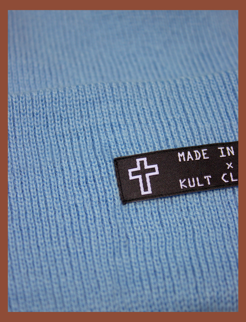 Close-up detail on the MADE IN HELL Beanie in Pastel Blue by KULT Clothing | Black appliqué label on the front of a pastel blue, 100% acrylic knit beanie hat