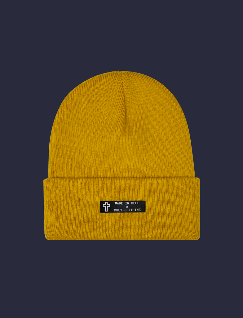 Front of the MADE IN HELL Beanie in Mustard by KULT Clothing | Black appliqué label on the front of a mustard-coloured, 100% acrylic knit beanie hat