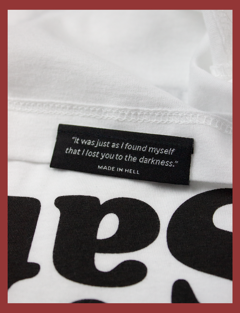 Close-up detailing of the underside hem label on THE JOY OF SATAN Tee in White by KULT Clothing | The Joy of Satan | A Gourmet Guide to Sinning | KVLT