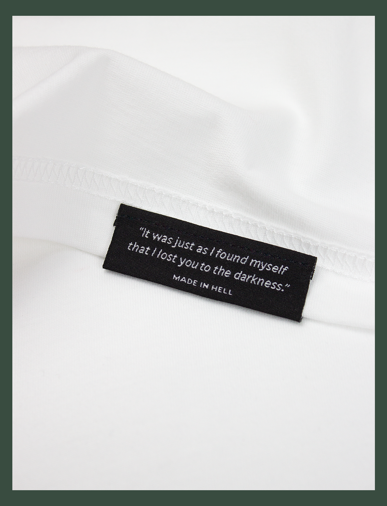 Close-up shot of the underside hem tag on the TIL DEATH Tee in White by KULT Clothing | eco-friendly, climate neutral t-shirt | "It was just as I found myself that I lost you to the darkness." MADE IN HELL